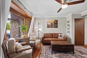 A living room with a brown sofa, a wooden coffee table, a chair, and a floor lamp.