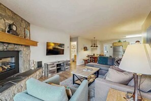 Ein Wohnzimmer mit Kamin aus Stein, einem Flachbildfernseher, einer Couch und einem Couchtisch.