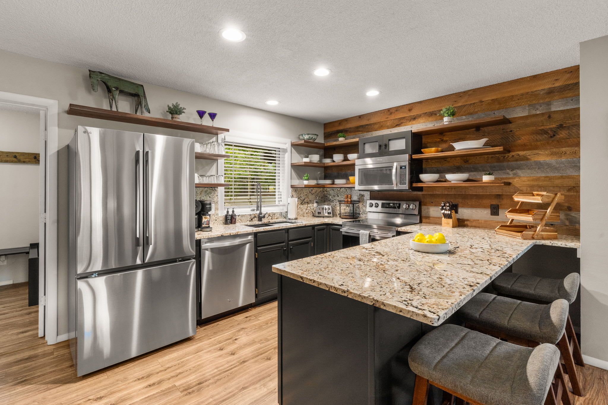 Une cuisine moderne dotée d’appareils électroménagers en acier inoxydable, de touches décoratives en bois et d’un plan de travail en granit.
