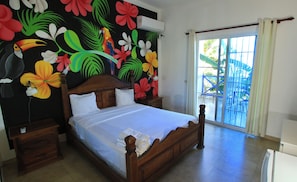 A bed with white linens, a wooden headboard, and a nightstand with a lamp.