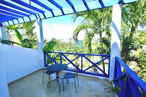 A balcony with a blue railing, two chairs, and a table.