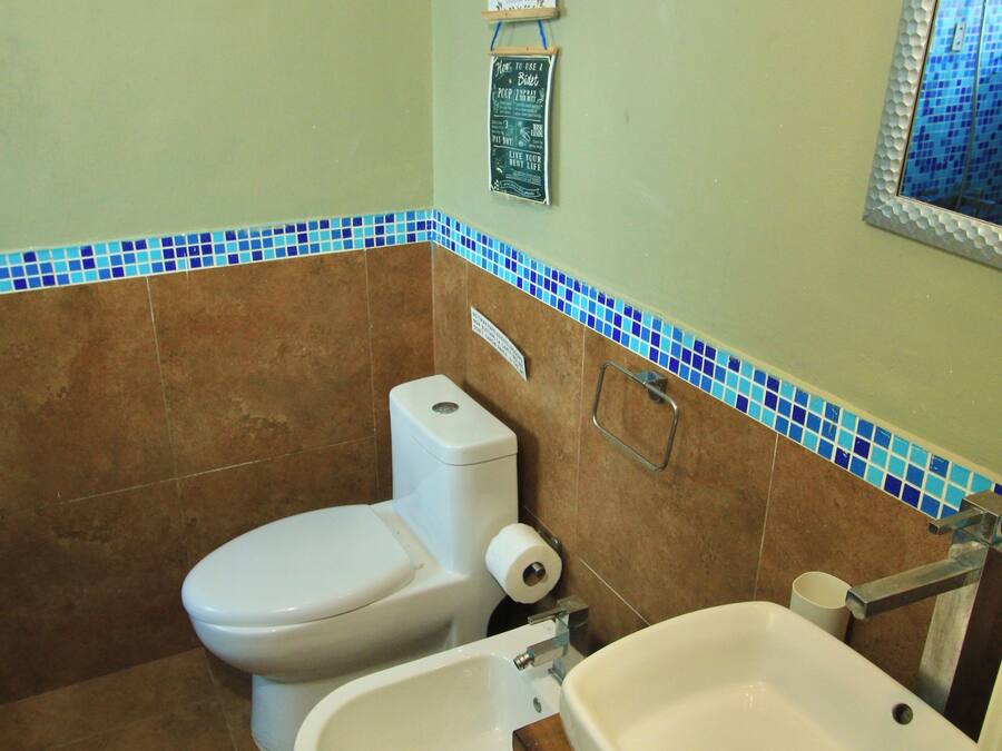 Un baño con inodoro, lavabo y paredes de azulejos.