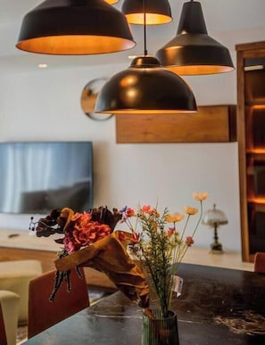 Ein Essbereich mit Pendelleuchten, einer Blumenvase und einem Holztisch.