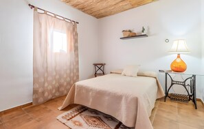 Ein Schlafzimmer mit einem Bett, einer Lampe, einem Regal mit Dekoration und einem kleinen Tisch.