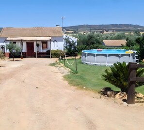 Ein Haus mit Swimmingpool, einer Schotterauffahrt und Blick auf die Hügel.
