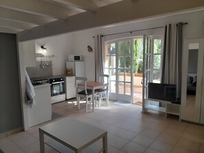 Eine kleine Küche mit Essbereich, einem Fernseher und einer Schiebetür, die auf eine Terrasse im Freien führt.