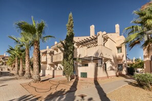 A residential building with a modern architectural style, featuring a central courtyard with palm trees and a pergola.