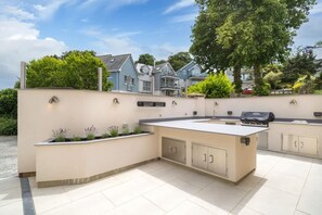 Ein Außenbereich mit Küche, inklusive eingebauter Arbeitsplatte, Schränken und Grill.