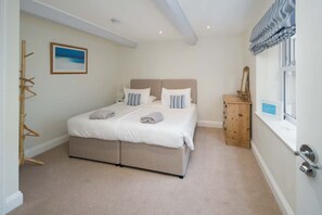 A bedroom with a double bed, a wooden cabinet, a window with curtains, and a painting on the wall. - The Watch House Waterfront Home With Solent Views (Cowes)