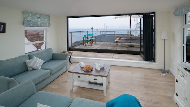 Een woonkamer met een bank, salontafel en uitzicht op een balkon met tuinmeubilair.