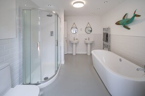A modern bathroom with a glass-enclosed shower, a large bathtub, two sinks, and decorative mirrors. - Windchasers Unique 3 bed Duplex With hot tub (Cowes)