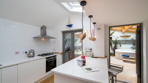 Eine moderne Küche mit weißen Schränken, einem Gasherd, einem Wasserkocher und einer Kaffeemaschine.