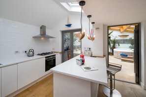 A modern kitchen with white cabinets, a gas stove, a kettle, and a coffee maker. - Windchasers Unique 3 bed Duplex With hot tub (Cowes)