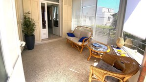 Un balcon agrémenté de meubles en osier, d’une plante en pot et offrant une vue sur l’extérieur.