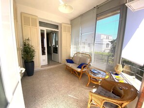Ein Balkon mit Korbmöbeln, einer Topfpflanze und Blick ins Freie.