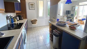 Une cuisine équipée d’un lave-linge, d’un évier, d’une poubelle et d’un coin repas avec une table et des chaises.
