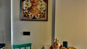 A dining area with a table, a chair, a vase, and a fruit bowl.
