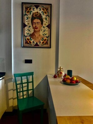 Un coin repas comprenant une table, une chaise, un vase et un saladier de fruits.