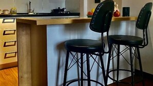 A kitchen with a stove, a black range hood, and two black bar stools.