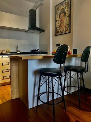 A kitchen with a stove, a black range hood, and two black bar stools.