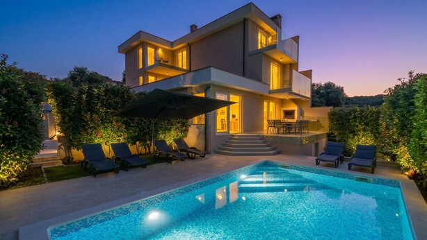 Una moderna casa a due piani con piscina, area salotto esterna e una scalinata che conduce al piano superiore.