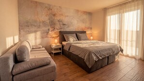 Una camera da letto con un letto, una poltrona, un comodino e una parete decorata con un murale strutturato.