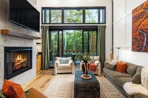 A modern living room with a fireplace, large windows, and a cozy seating area.