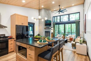 A modern kitchen with a central island, wooden cabinets, and a dining area with a view of the outdoors.
