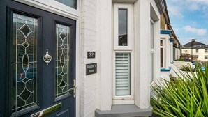 Ein Wohngebäude mit schwarzer Haustür, einem kleinen Fenster mit Rollläden und einem Hausnummernschild mit der Aufschrift '22'.