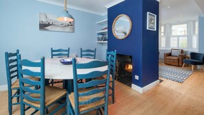 Ein Essbereich mit einem runden Tisch, blauen Stühlen, einer Pendelleuchte und einem Kamin.