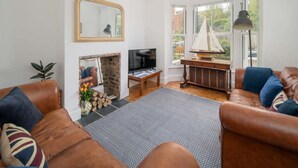 A living room with a fireplace, television, and a sailboat model. - Seabreeze House Stylish 3 bed Townhouse (Cowes)