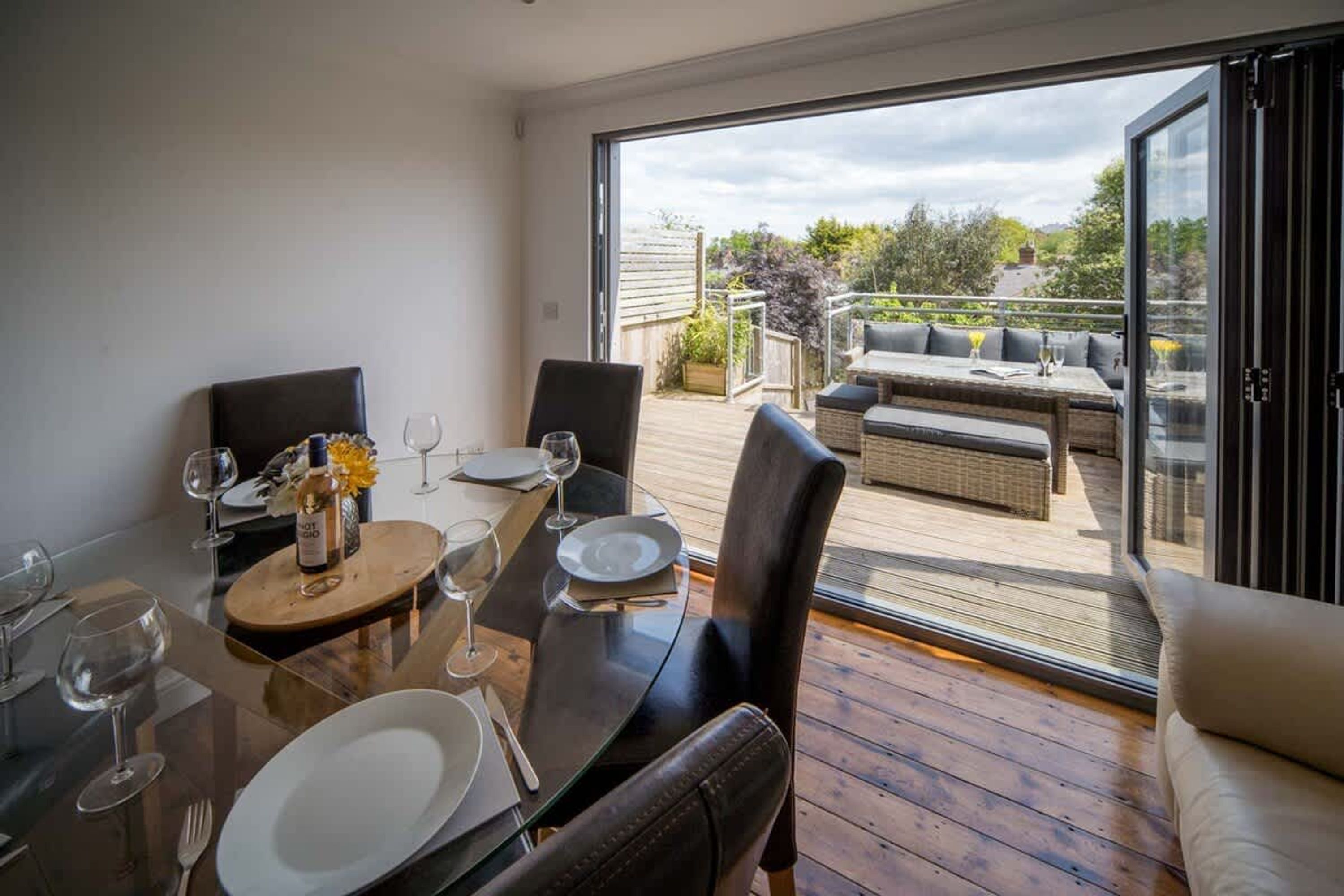 A dining area with a table set for four, a sofa, and a view of the outdoors.