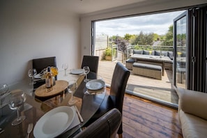 A dining area with a table set for four, a sofa, and a view of the outdoors. - Seabreeze House Stylish 3 bed Townhouse (Cowes)