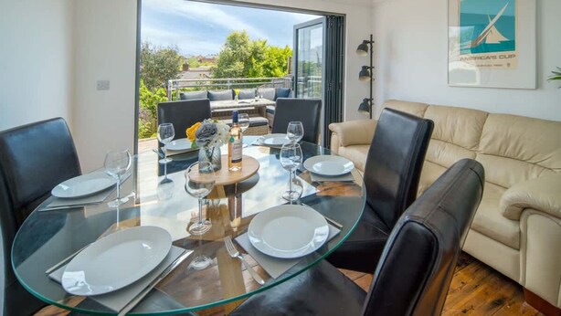A dining area with a glass table, chairs, and a view of the outdoors. - Seabreeze House Stylish 3 bed Townhouse (Cowes)