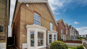 A two-story residential building with a bay window, a small garden, and a brick facade. - Seabreeze House Stylish 3 bed Townhouse (Cowes)