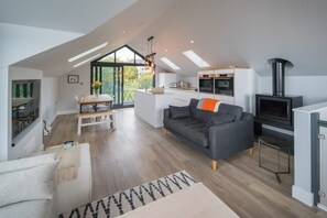 A modern loft with a dining area, kitchen, and living space, featuring skylights and a fireplace. - Rotherwood Luxury Home Steps From Gurnard Beach (Cowes)