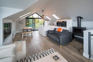 A modern loft-style living space with a kitchen, dining area, and a fireplace. - Rotherwood Luxury Home Steps From Gurnard Beach (Cowes)
