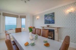 A dining room with a view, a fireplace, and a painting on the wall. - Seaview Apartment 2 Bed Solent Views Parking (Cowes)