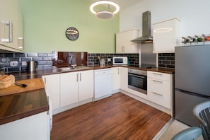 Eine moderne Küche mit weißen Schränken, einer Mikrowelle, einem Backofen und einem Kühlschrank aus Edelstahl.