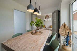 A dining area with a long table, chairs, hanging pendant lights, and a potted plant. - Spring Hill Luxury Home Countryside Solent Views (Freshwater)