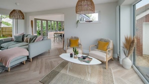 A modern living room with a sofa, chairs, a coffee table, and a dining area. - Spring Hill Luxury Home Countryside Solent Views (Freshwater)