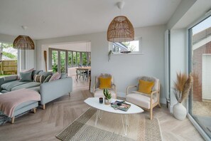 A modern living room with a sofa, chairs, a coffee table, and a dining area. - Spring Hill Luxury Home Countryside Solent Views (Freshwater)