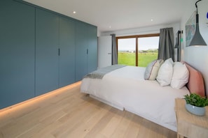 A bedroom with a bed, a large window, and a view of a green field. - Spring Hill Luxury Home Countryside Solent Views (Freshwater)