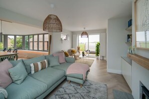 A modern living room with a sectional sofa, a dining area, and a kitchen. - Spring Hill Luxury Home Countryside Solent Views (Freshwater)