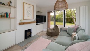 A modern living room with a sofa, a television, a fireplace, and a large window. - Spring Hill Luxury Home Countryside Solent Views (Freshwater)