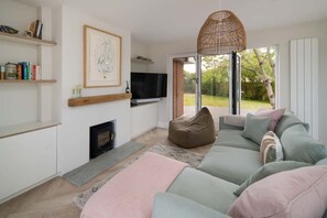 A modern living room with a sofa, a television, a fireplace, and a large window. - Spring Hill Luxury Home Countryside Solent Views (Freshwater)