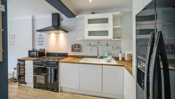 Een moderne keuken met een ingebouwde oven, magnetron en kookplaat, een spoelbak en bovenkasten.