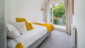 Een slaapkamer met een bed, een raam en een radiator.