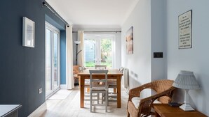 Een kamer met een eettafel, stoelen, een lamp en een schilderij aan de muur.