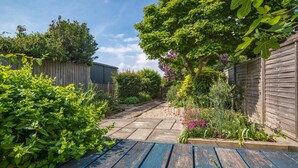 A garden with a wooden fence, a pathway, and various plants. - Lily Cottage Charming Gurnard Retreat by the Sea (Cowes)
